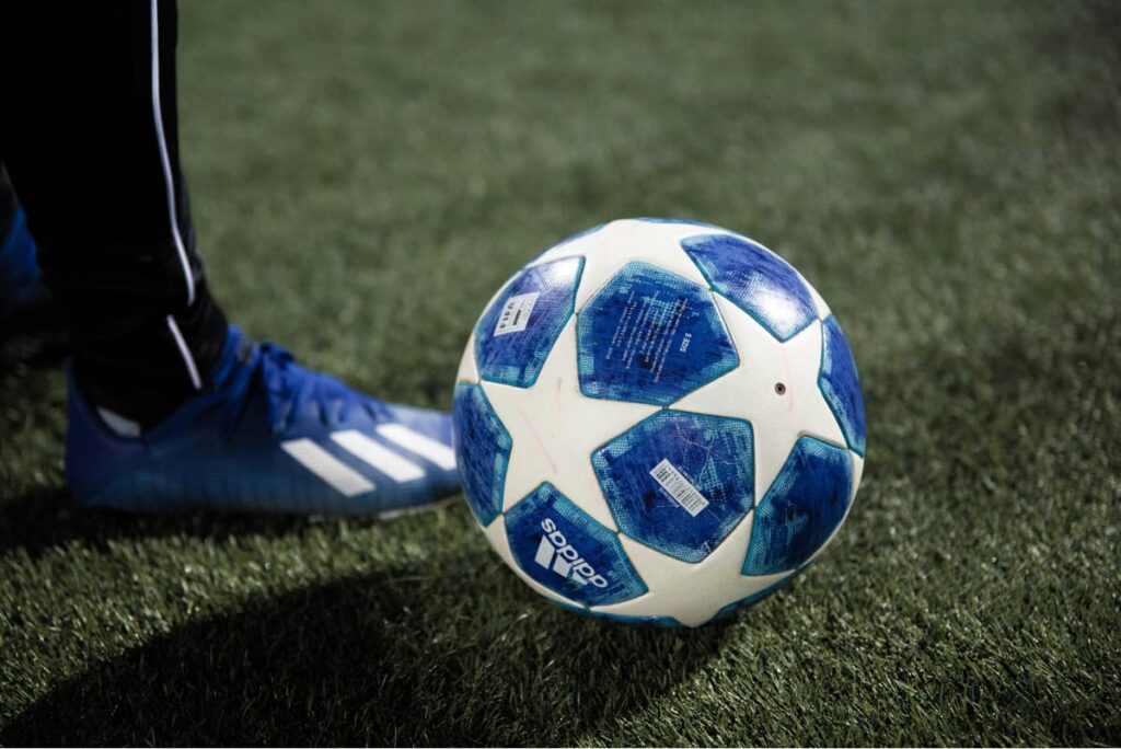a close up of a blue and white football and a soccer player ready to strike the ball