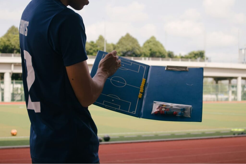 coach pointing at soccer tactics board with positions