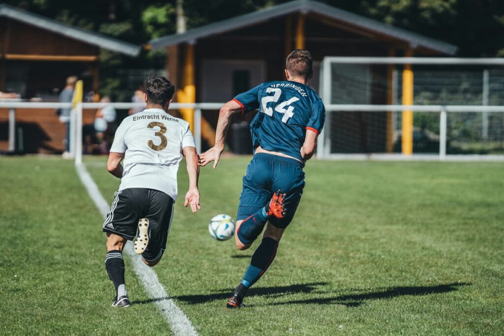 2 soccer players sprinting after a ball